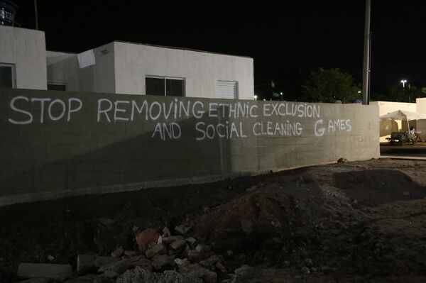 Graffiti on a wall reads: “Stop removing, ethnic exclusion and social cleansing games.” - Sputnik International