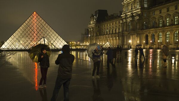 Chinese tourists take at night photos of each other outside the main entrance to the Louvre museum and its pyramid, on March 24, 2015 in Paris. (File) - Sputnik International
