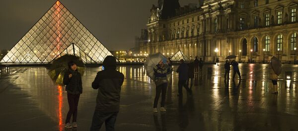 Chinese tourists take at night photos of each other outside the main entrance to the Louvre museum and its pyramid, on March 24, 2015 in Paris. (File) - Sputnik International