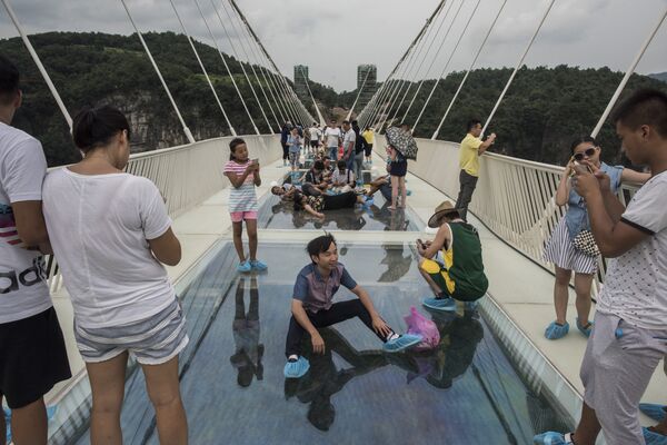 A tourist poses for a photograph on the world's highest and longest glass-bottomed bridge above a valley in Zhangjiajie in China's Hunan Province on August 20, 2016 A tourist poses for a photograph on the world's highest and longest glass-bottomed bridge above a valley in Zhangjiajie in China's Hunan Province on August 20, 2016 - Sputnik International