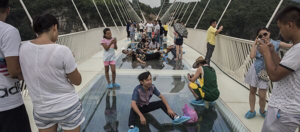 A tourist poses for a photograph on the world's highest and longest glass-bottomed bridge above a valley in Zhangjiajie in China's Hunan Province on August 20, 2016 A tourist poses for a photograph on the world's highest and longest glass-bottomed bridge above a valley in Zhangjiajie in China's Hunan Province on August 20, 2016 - Sputnik International