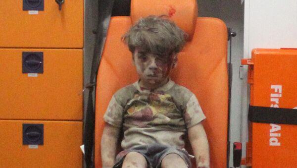 Five-year-old Omran Daqneesh, with bloodied face, sits inside an ambulance after he was rescued following an airstrike in the rebel-held al-Qaterji neighbourhood of Aleppo, Syria August 17, 2016 - Sputnik International