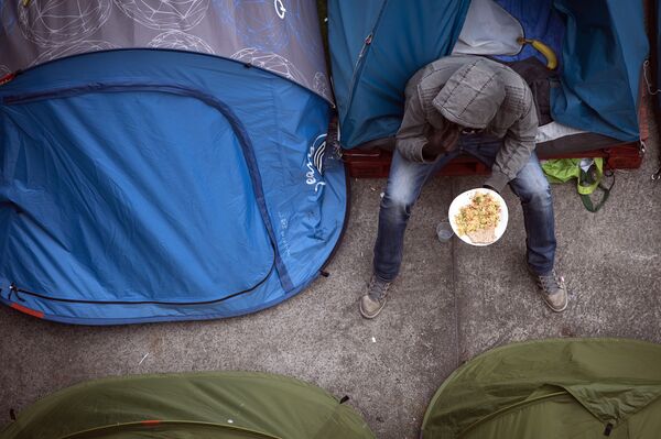 A migrant eats a meal outside his tent after it was distributed by volunteers, in a camp located next to the Austerlitz station in Paris, on June 14, 2015 A migrant eats a meal outside his tent after it was distributed by volunteers, in a camp located next to the Austerlitz station in Paris, on June 14, 2015 - Sputnik International
