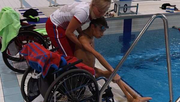 The coach Olesya Alexandrova helps paralympic swimmer Alexander Makarov, member of Russia's Paralympic national team, after a training session in the town of Ruza, 100 km west of Moscow, on August 18, 2016 - Sputnik International