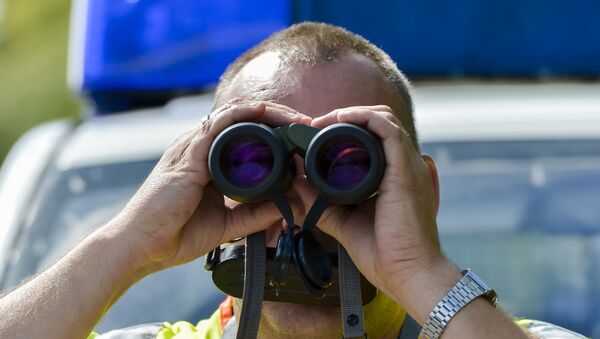 A police officer uses binoculars at a check point during control on the border crossing between Austria and Germany at the southern German city of Kiefersfelden on September 16, 2015 - Sputnik International