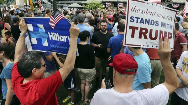 A supporter of Democratic presidential candidate Hillary Clinton and a Republican presidential candidate Donald Trump supporter hold signs as they attend a Memorial Day parade Monday, May 30, 2016, in Chappaqua, N.Y. Clinton and her husband former President Bill Clinton, along with New York Gov. Andrew Cuomo, walked in the parade - Sputnik International