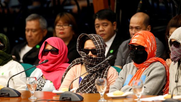 Family members of people alleged by police as drug pushers and were killed during an illegal drugs meth raid, wear masks during a Senate hearing regarding people killed during a crackdown on illegal drugs in Pasay, Metro Manila, Philippines August 23, 2016. - Sputnik International
