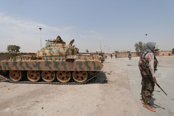 A Kurdish fighter from the People's Protection Units (YPG) carries his weapon as he stands past a tank in the Ghwairan neighborhood of Hasakah, Syria, August 22, 2016. A Kurdish fighter from the People's Protection Units (YPG) carries his weapon as he stands past a tank in the Ghwairan neighborhood of Hasakah, Syria, August 22, 2016. - Sputnik International