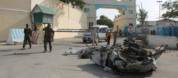 Somali soldiers walk past the wreckage of a car bomb by the main gate outside the presidential palace in Mogadishu (File) - Sputnik International