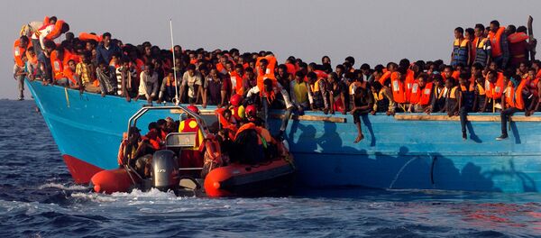 A rescue boat of the Spanish NGO Proactiva approaches an overcrowded wooden vessel with migrants from Eritrea, off the Libyan coast in Mediterranean Sea August 29, 2016 A rescue boat of the Spanish NGO Proactiva approaches an overcrowded wooden vessel with migrants from Eritrea, off the Libyan coast in Mediterranean Sea August 29, 2016 - Sputnik International