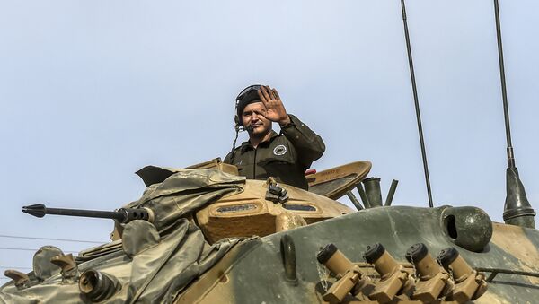 This picture taken around 5 kilometres west from the Turkish Syrian border city of Karkamis in the southern region of Gaziantep, on August 25, 2016 shows a soldier gesturing as Turkish Army tanks drive to the Syrian Turkish border town of Jarabulus - Sputnik International