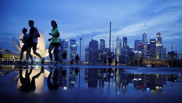 Joggers run past as the skyline of Singapore's financial district is seen in the background - Sputnik International
