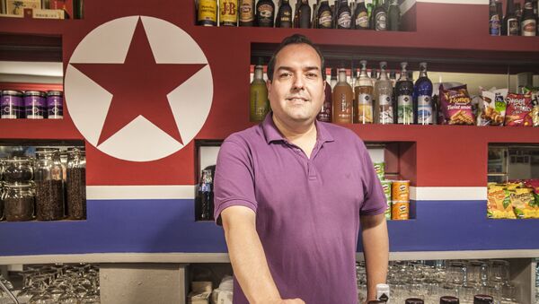 Alejandro Cao de Benós poses in Café Pyongyang with North Koeran flag on the background - Sputnik International