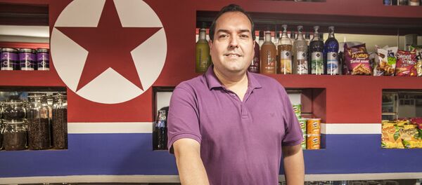Alejandro Cao de Benós poses in Café Pyongyang with North Koeran flag on the background Alejandro Cao de Benós poses in Café Pyongyang with North Koeran flag on the background - Sputnik International