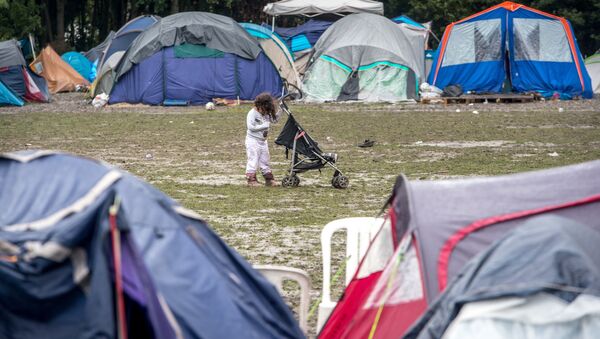 A girl stand behind a stroller in a makeshift camp in Grande-Synthe. (File) - Sputnik International