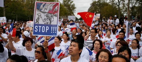 Demonstrators hold signs at a rally of the Chinese community to raise awareness about recent racists attacks in Paris, France, September 4, 2016. - Sputnik International