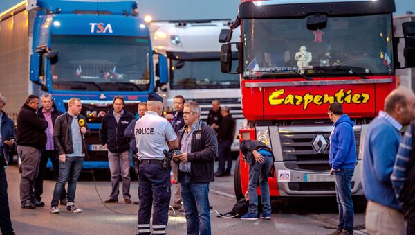 A man speaks with a police officer as a dozen of truck drivers gather in a parking on September 5, 2016 in Loon Plage prior to a slow-down operation on the A16 highway to ask for the dismantling of the so-called Jungle migrant camp in the French northern port city of Calais - Sputnik International