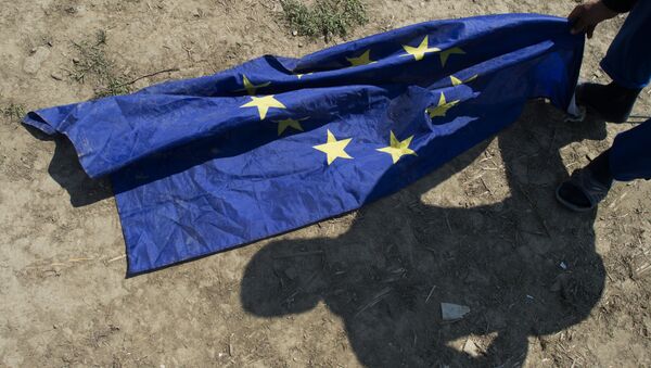 A migrant from Afghanistan grabs for an EU flag next to his tent at a makeshift camp for migrants and refugees near the village of Idomeni not far from the Greek-Macedonian border on May 1, 2016. - Sputnik International
