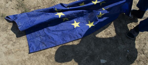 A migrant from Afghanistan grabs for an EU flag next to his tent at a makeshift camp for migrants and refugees near the village of Idomeni not far from the Greek-Macedonian border on May 1, 2016. - Sputnik International