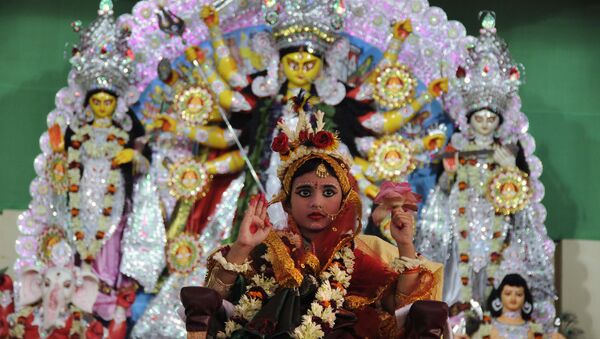 A young Indian Hindu unmarried girl, Nilanjana Chakraborty (5), known as a 'kumari' and dressed as the Hindu goddess Durga, puts her hand up during a ritual for the Durga Puja festival at Ramakrishna Mission in Agartala, the capital of northeastern state of Tripura on October 21, 2015 - Sputnik International