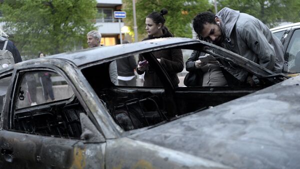 People inspect a car gutted by fire in the Stockholm suburb of Rinkeby - Sputnik International