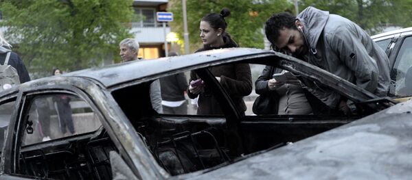 People inspect a car gutted by fire in the Stockholm suburb of Rinkeby - Sputnik International