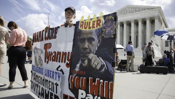 Ronald Brock moves his anti-Obamacare sign as protestors, press, and passersby wait for decisions in the final days of the Supreme Court's term, in Washington, Wednesday, June 25, 2014 - Sputnik International