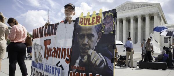 Ronald Brock moves his anti-Obamacare sign as protestors, press, and passersby wait for decisions in the final days of the Supreme Court's term, in Washington, Wednesday, June 25, 2014 - Sputnik International