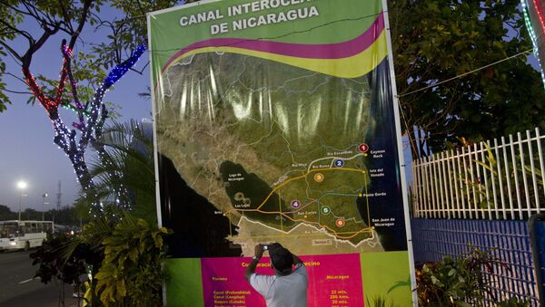 In this Dec. 4, 2013 photo, Oscar Torres, a 62-year-old retired construction worker takes photos of a banner showing a map of Nicaragua with possible routes of the Inter-Oceanic canal in Managua, Nicaragua - Sputnik International