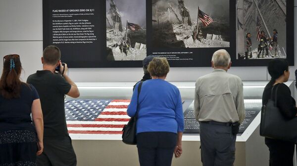 Visitors view the display for the American flag, left, that firefighters hoisted at ground zero in the hours after the 9/11 terror attack  at the Sept. 11 museum in New York - Sputnik International