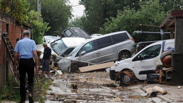 People walk through a street where cars have piled due to overnight flooding, after storms in the village of Stajkovci, just east of Skopje, Macedonia, Sunday, Aug. 7, 2016. - Sputnik International