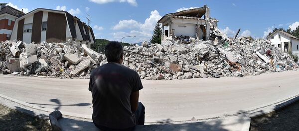 A man sits in front of collapsed houses following the earthquake in Amatrice, central Italy, August 30, 2016 - Sputnik International