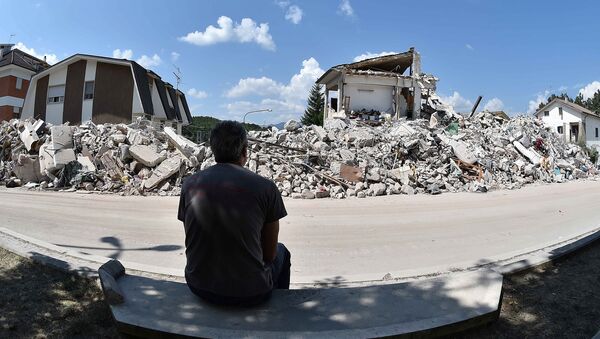 A man sits in front of collapsed houses following the earthquake in Amatrice, central Italy, August 30, 2016 - Sputnik International
