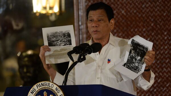 Philippine President Rodrigo Duterte holds up a photo and cites accounts of US troops who killed Muslims during the US's occupation of the Philippines in the early-1900s, during a speech at the Malacanang palace in Manila on September 12, 2016 - Sputnik International