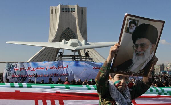 An Iranian boy holds a portrait of supreme leader, Ayatollah Ali khamenei as he walks past a replica of the captured US RQ-170 drone on display next to the Azadi (Freedom) tower during the 33rd anniversary of the Islamic revolution in Tehran on February 11, 2012 - Sputnik International
