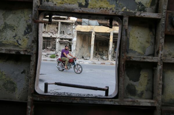 A man rides a motocycle near damaged buildings in the rebel held Old Aleppo, Syria, September 14, 2016 - Sputnik International