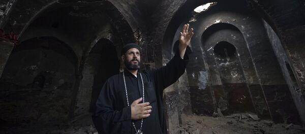 Delga's Coptic priest Yuannas points at the damage in the historical Blessed Virgin church following an attack by masked Islamist men the previous month in the town of Delga, in the central Egyptian province of Minya, some of 400 kilometres south of Cairo, on September 29, 2013 - Sputnik International