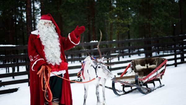 Santa Claus waves as he stands with a reindeer and sled outside Rovaniemi, Finnish Lapland on December 15, 2011 - Sputnik International
