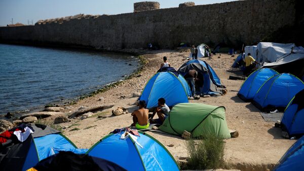 Refugees and migrants sit next to tents set on the beach next to a medieval fortification wall, at the Souda municipality run camp for refugees and migrants, on the island of Chios, Greece, September 7, 2016. - Sputnik International