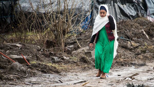 A migrant woman walks along a muddy path in the so-called Jungle refugee and migrant camp in Calais, on February 24, 2016. - Sputnik International