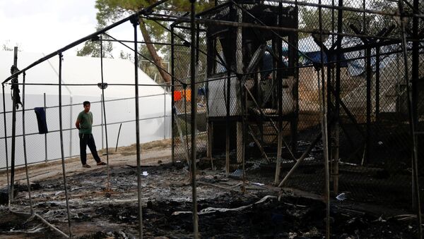 A migrant stands next to a burned tent at the Moria migrant camp, after a fire that ripped through tents and destroyed containers during violence among residents, on the island of Lesbos, Greece, September 20, 2016. - Sputnik International