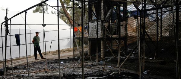 A migrant stands next to a burned tent at the Moria migrant camp, after a fire that ripped through tents and destroyed containers during violence among residents, on the island of Lesbos, Greece, September 20, 2016. - Sputnik International