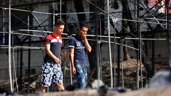A migrant (R) reacts as he walks next to the remains of burned tents at the Moria migrant camp, after a fire that ripped through tents and destroyed containers during violence among residents, on the island of Lesbos, Greece, September 20, 2016. - Sputnik International