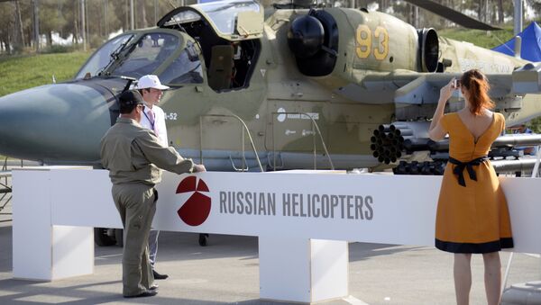 A woman as she takes a photo of a Russian military helicopter KA-52 at the ADEX 2014 International Defence Industry Exhibition in Baku on September 11, 2014 - Sputnik International
