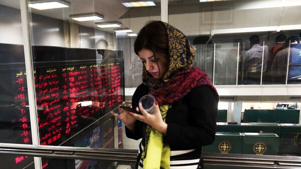 An Iranian woman uses a mobile phone next to a stock market activity board at the stock exchange in the capital Tehran on July 27, 2015 - Sputnik International