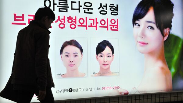 A pedestrian walks past an advertisement for plastic surgery clinic at a subway station in Seoul on March 26, 2014 - Sputnik International