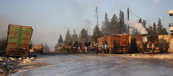 Syrians gather near damaged trucks carrying aid on the side of the road in the town of Orum al-Kubra on the western outskirts of the northern Syrian city of Aleppo on September 20, 2016, the morning after a convoy delivering aid was hit by a deadly air strike Syrians gather near damaged trucks carrying aid on the side of the road in the town of Orum al-Kubra on the western outskirts of the northern Syrian city of Aleppo on September 20, 2016, the morning after a convoy delivering aid was hit by a deadly air strike - Sputnik International