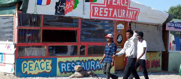 Migrants pass by the Peace Restaurant in the northern area of the camp called the Jungle in Calais, France, September 7, 2016 - Sputnik International