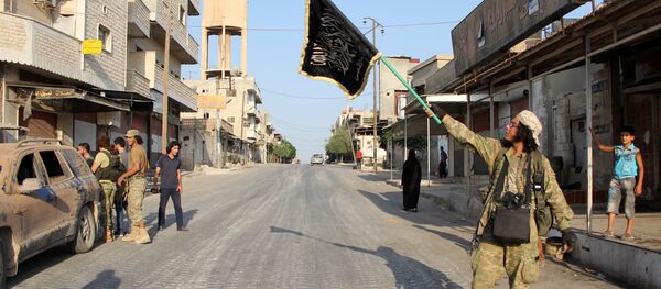 A terrorist from the Jund al-Aqsa group raises an Islamist flag after taking control of the northern Syrian town of Tayyibat al-Imam, northwest of Hama from Syrian government forces on August 31, 2016 - Sputnik International