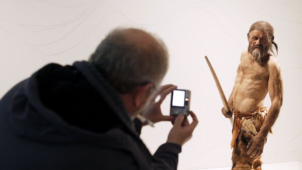 A man takes pictures of a statue representing an iceman named Oetzi, discovered on 1991 in the Italian Schnal Valley glacier, is displayed at the Archaeological Museum of Bolzano on February 28, 2011 during an official presentation of the reconstrution - Sputnik International